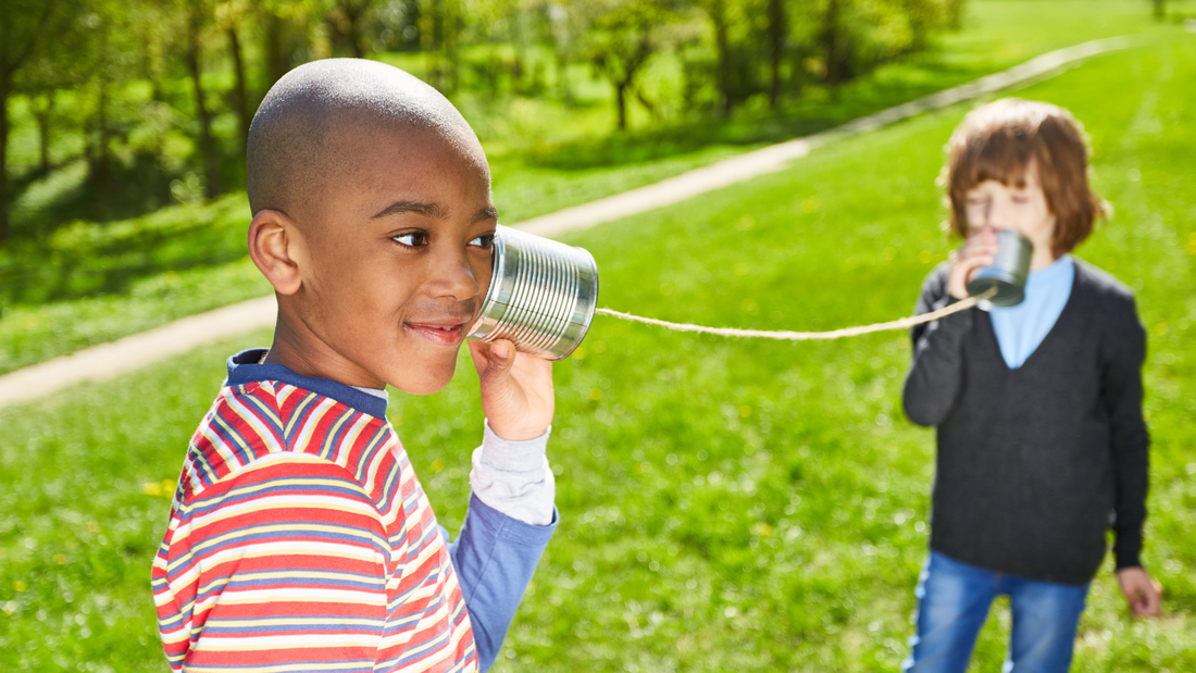 Two children speak through tin can phones.