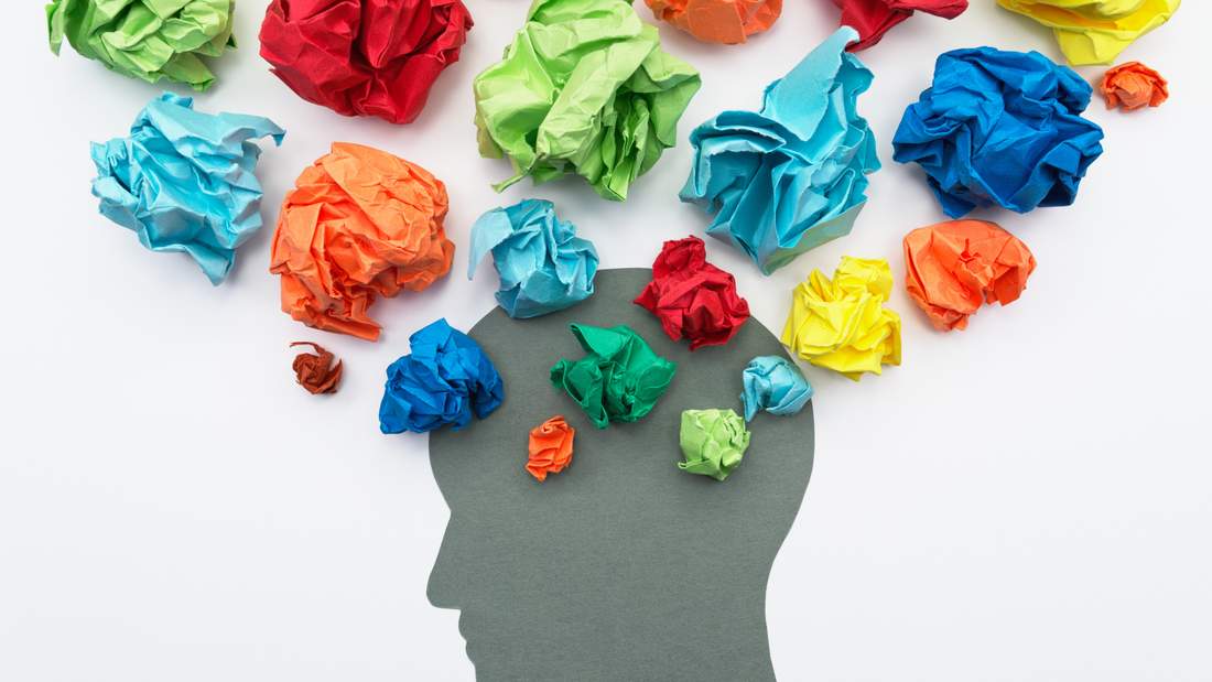 The silhouette of a head with colored papers crumpled up around it. 