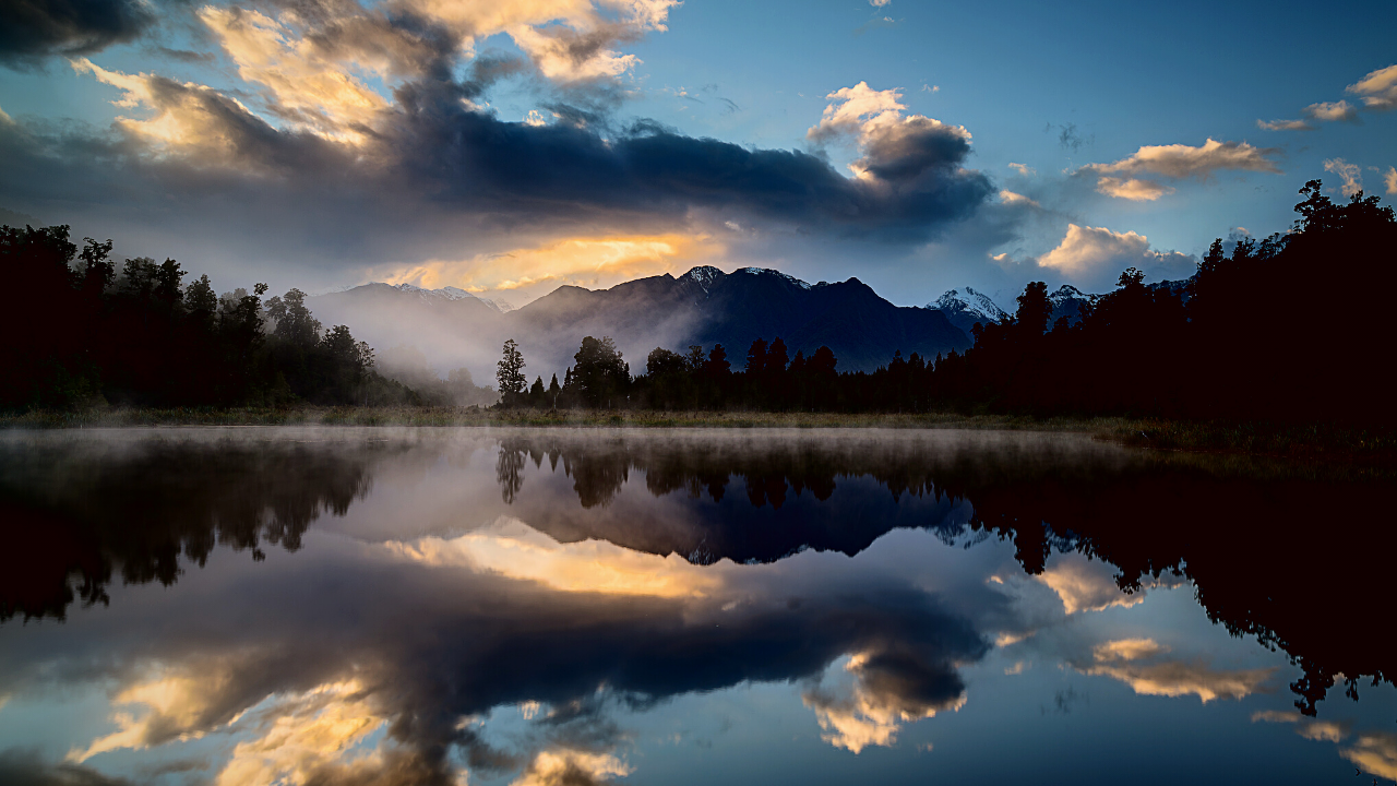 A mountain scene reflects in a gentle lake.