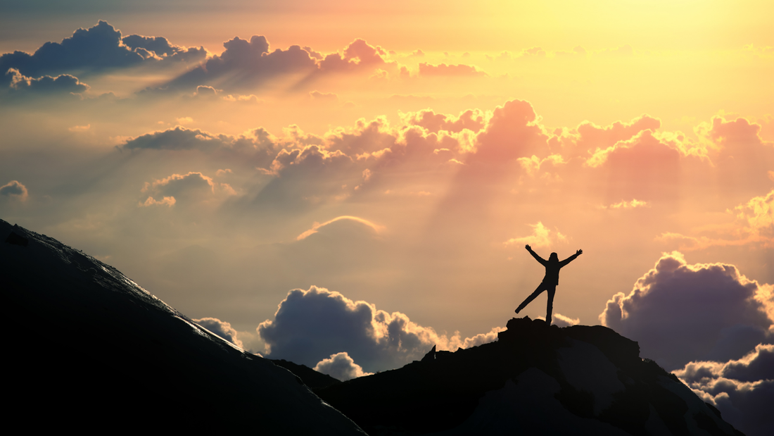 A person stand atop a mountain, joyful, singing, with a sun high in the sky.