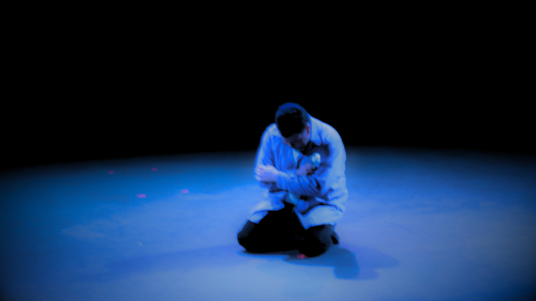 The author kneeling on stage, surrounded in blue.