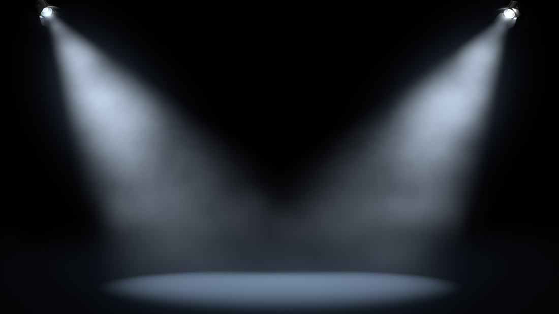 An empty stage with two spotlights shining center stage.