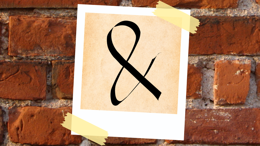 A Polaroid picture of the ampersand taped to a brick wall.