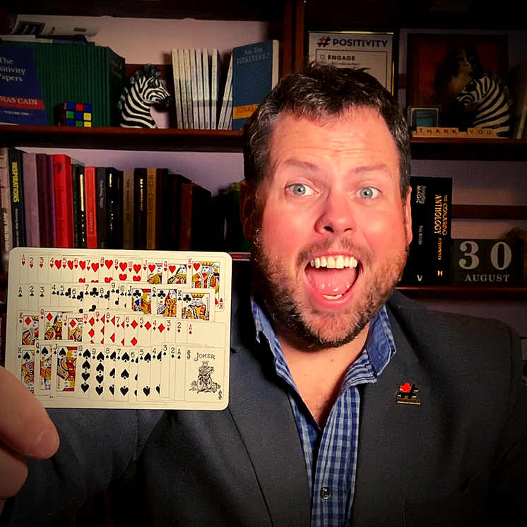 In this picture, Jonas Cain is holding a playing card that has all 52 playing cards from a deck of cards printed on the single card.