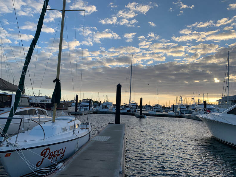 The sailboat, Poppy, docked at a marina at sunset.