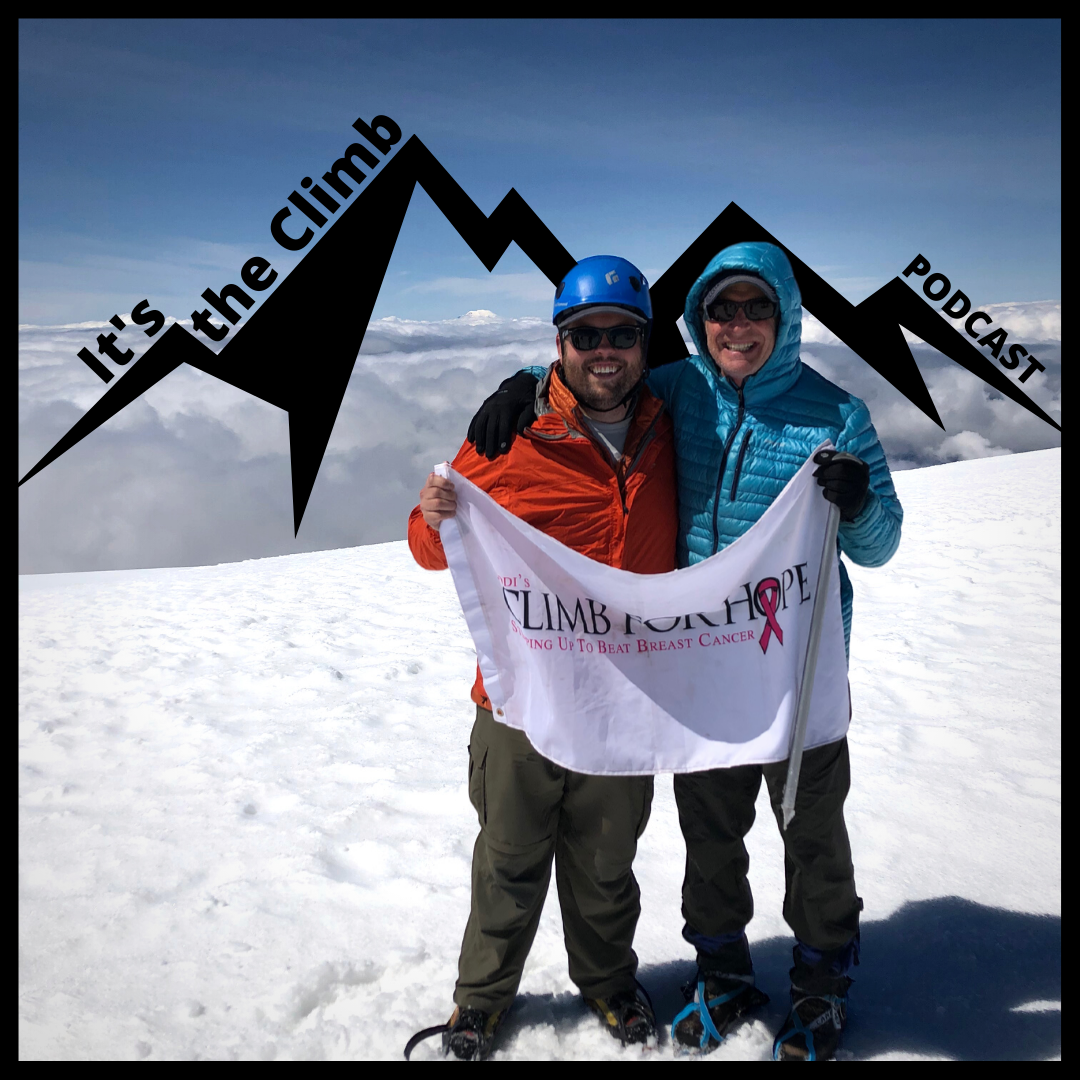 Jonas Cain and Andrew Buerger stand on the summit of a snowcapped Mt. Adams holding a Climb for Hope flag.